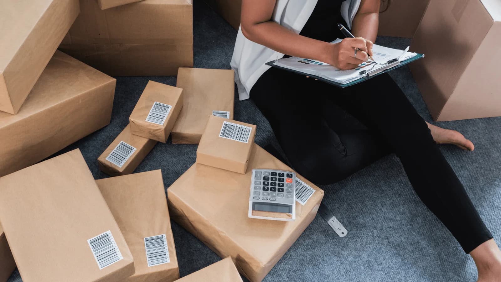 Hands packaging items, hinting at e-commerce accounting and tax considerations.