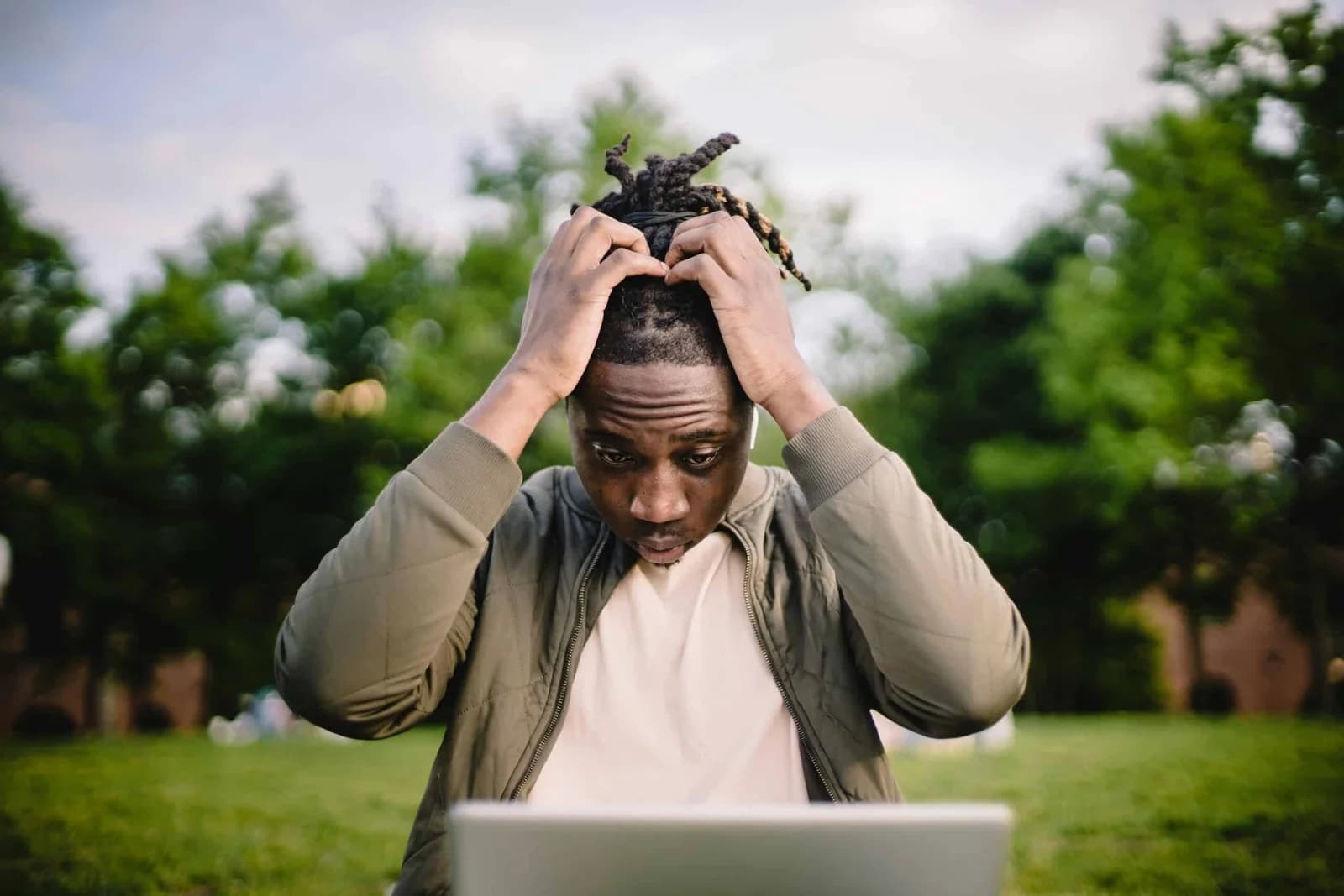 A person feeling stressed and holding their head in frustration while using a laptop.