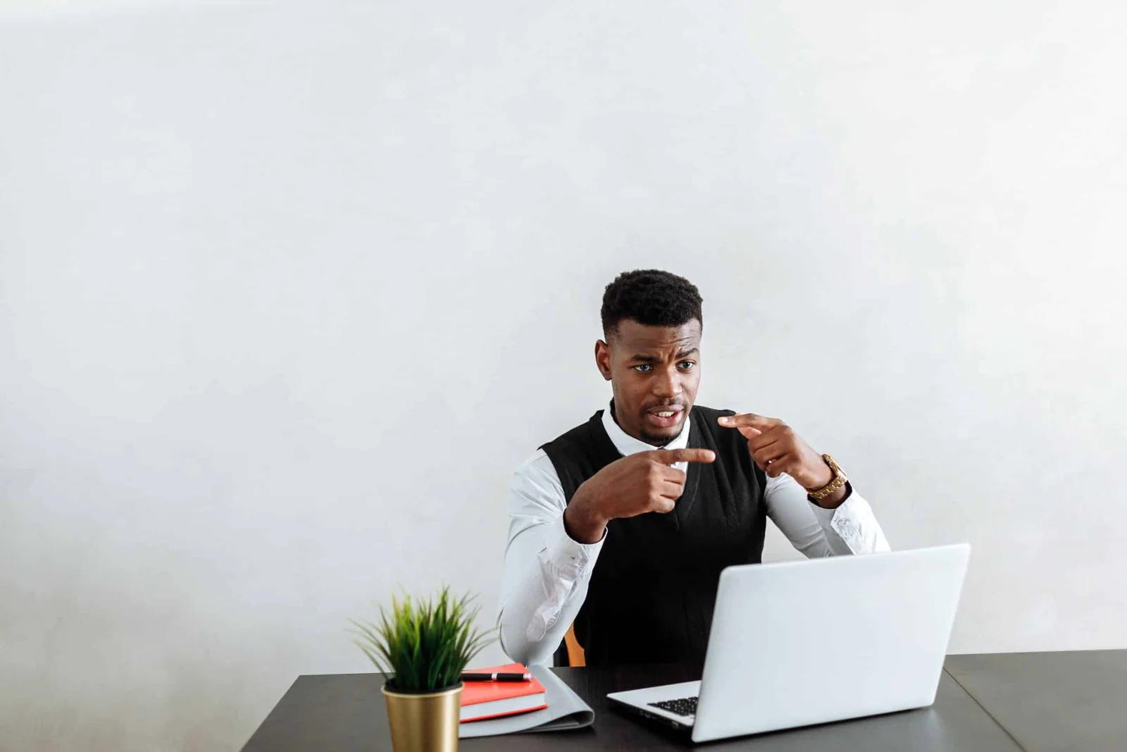 A person working at a desk with a laptop and taking notes.
