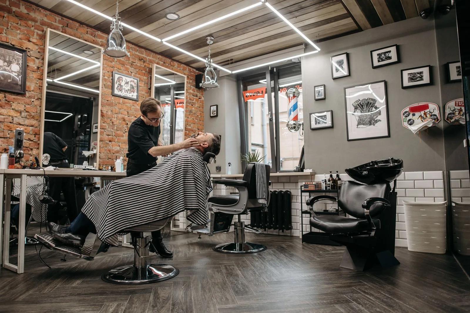 A busy UK barbershop with stylists working at chairs, illustrating chair rent and self-employed tax for barbers and salons