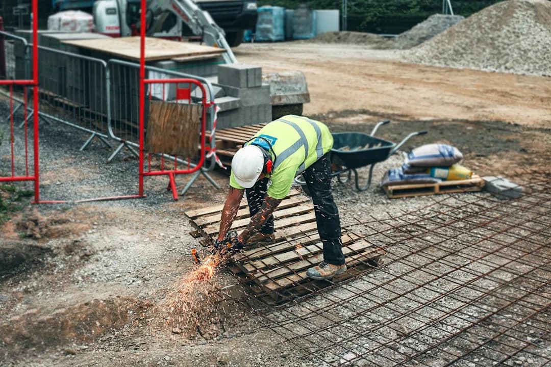 A construction subcontractor reviewing CIS paperwork on a tablet at a building site office