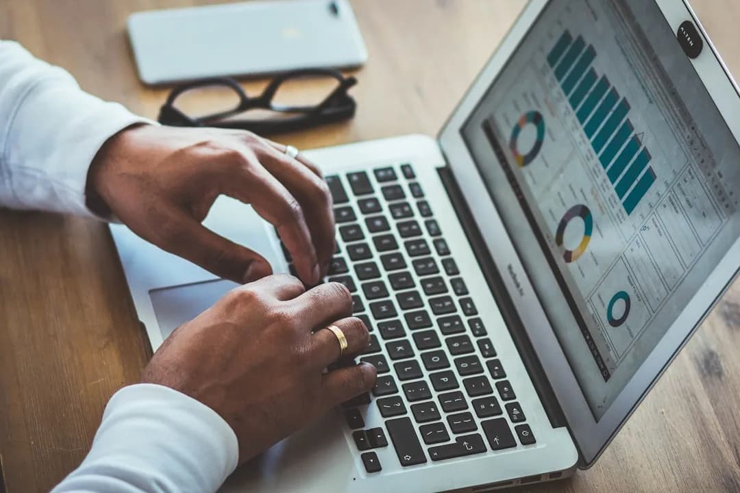 A small business owner matching bank statement lines to bookkeeping records on a laptop