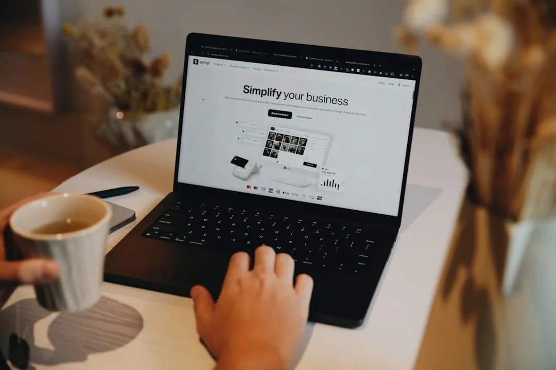 UK small business owner comparing ecommerce platforms on a laptop while packing orders