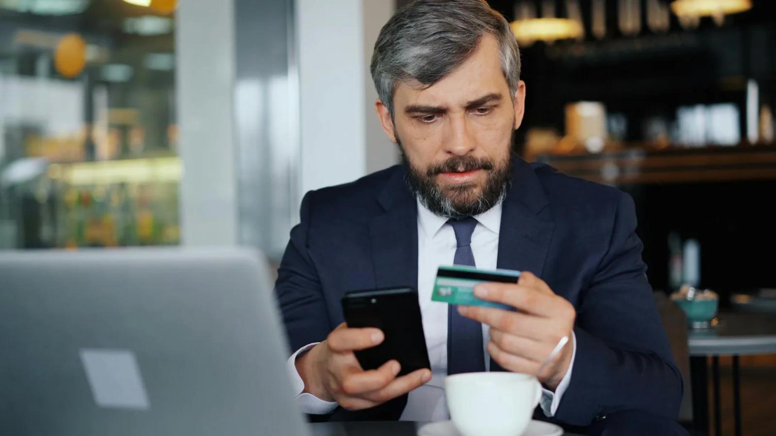 A small business owner reviewing business bank account statements and fees on a laptop at a desk