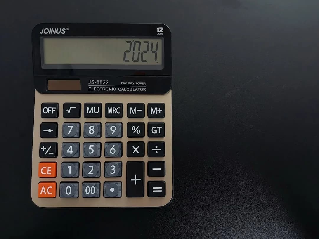An Amazon seller working out the VAT element of a selling price on a calculator and laptop