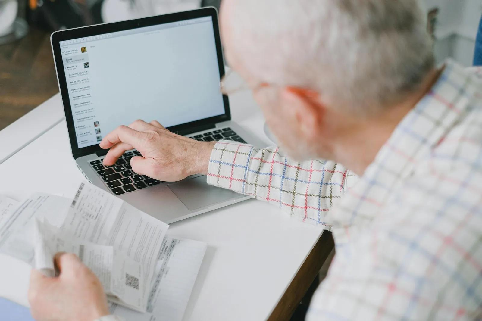 A UK taxpayer reviewing bank statements and a tax return at a kitchen table with a laptop