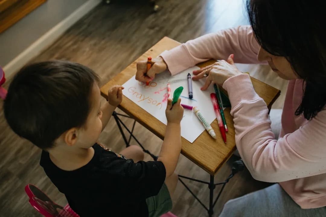 A childminder and her assistant supervising young children playing in a home setting