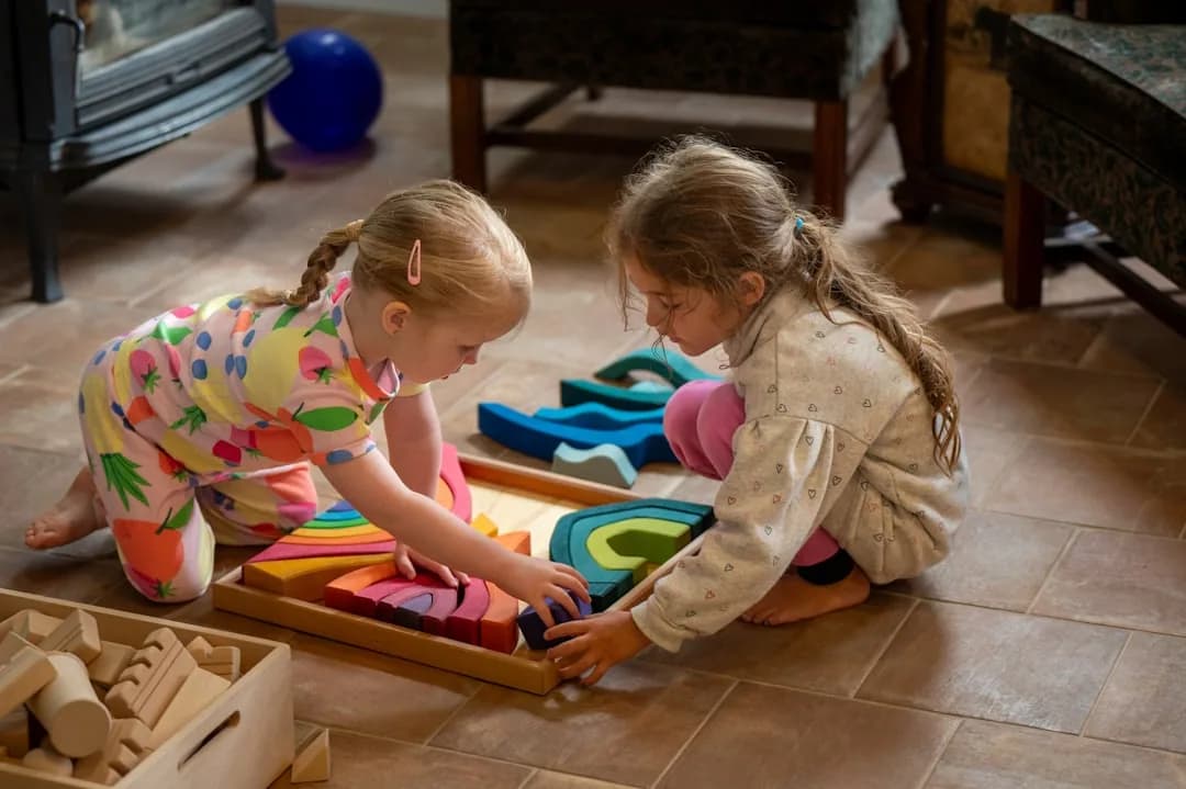A childminder at a kitchen table reviewing paperwork while children play, weighing up business structure