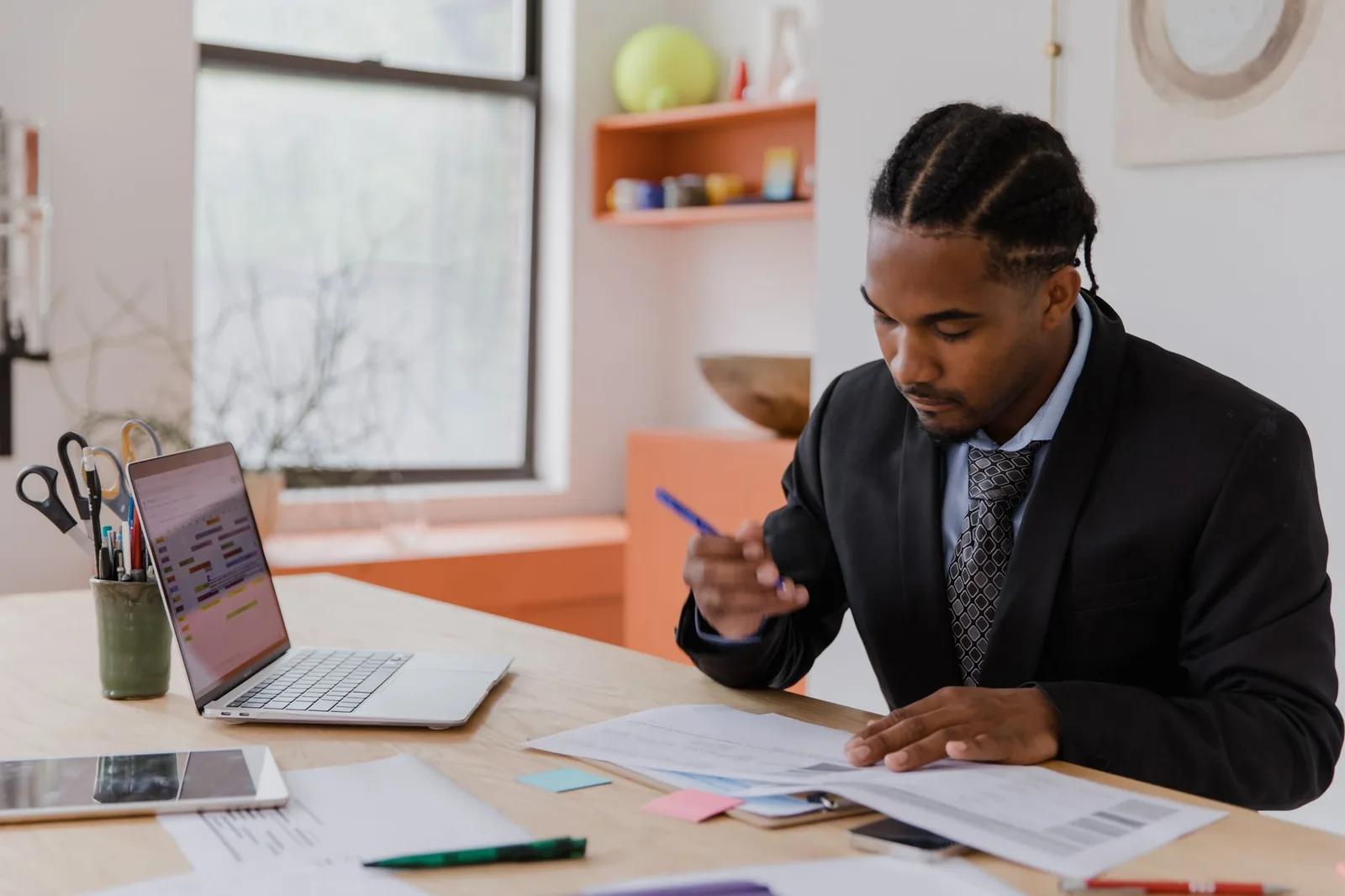 A limited company director reviewing dividend vouchers and a winding-up statement at a desk with a laptop showing HMRC tax rates