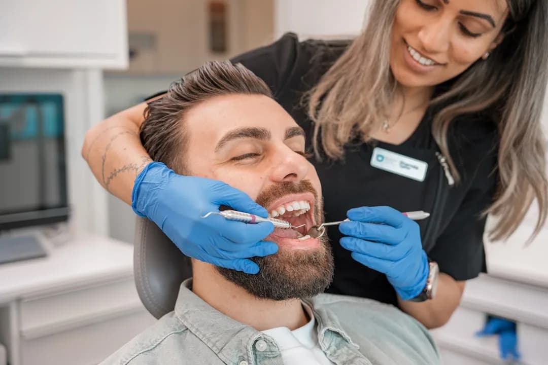 A dental hygienist treating a patient in a UK practice while reviewing engagement terms
