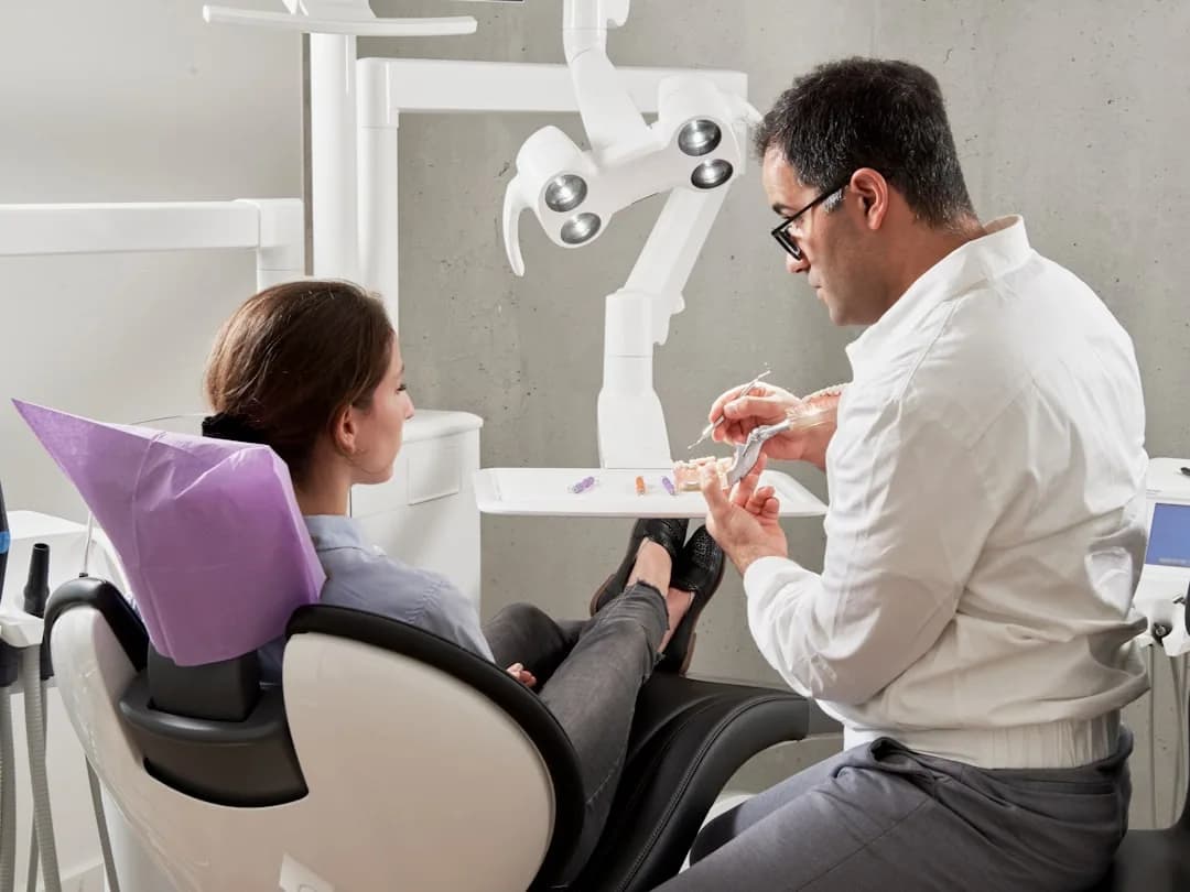 A dental practice owner reviewing VAT records at a desk with a laptop and patient invoices