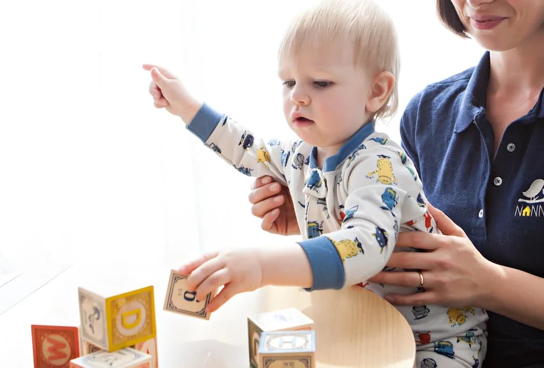 A registered childminder doing paperwork at a kitchen table while children play, working out tax