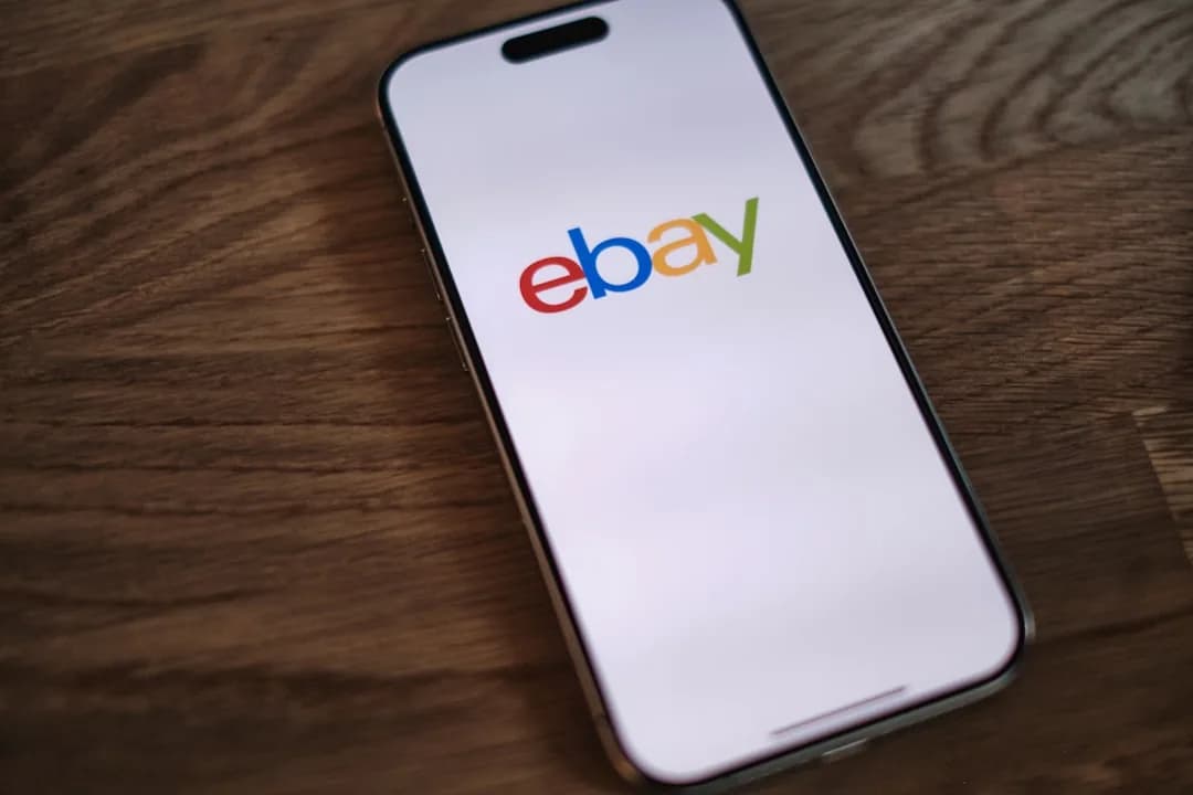 A UK eBay seller packing parcels at a desk while reviewing sales figures on a laptop