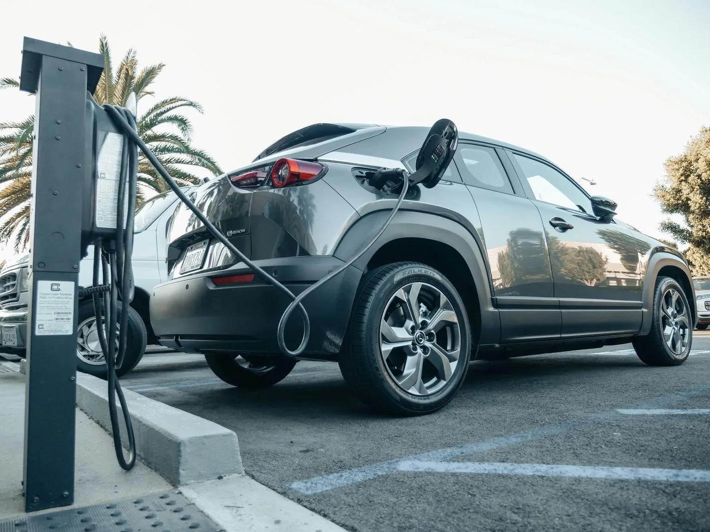 Electric company car charging outdoors with a cable plugged into a roadside charge point