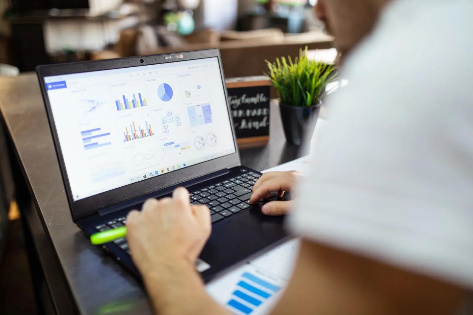 Person analysing financial charts and graphs on a laptop in a modern office