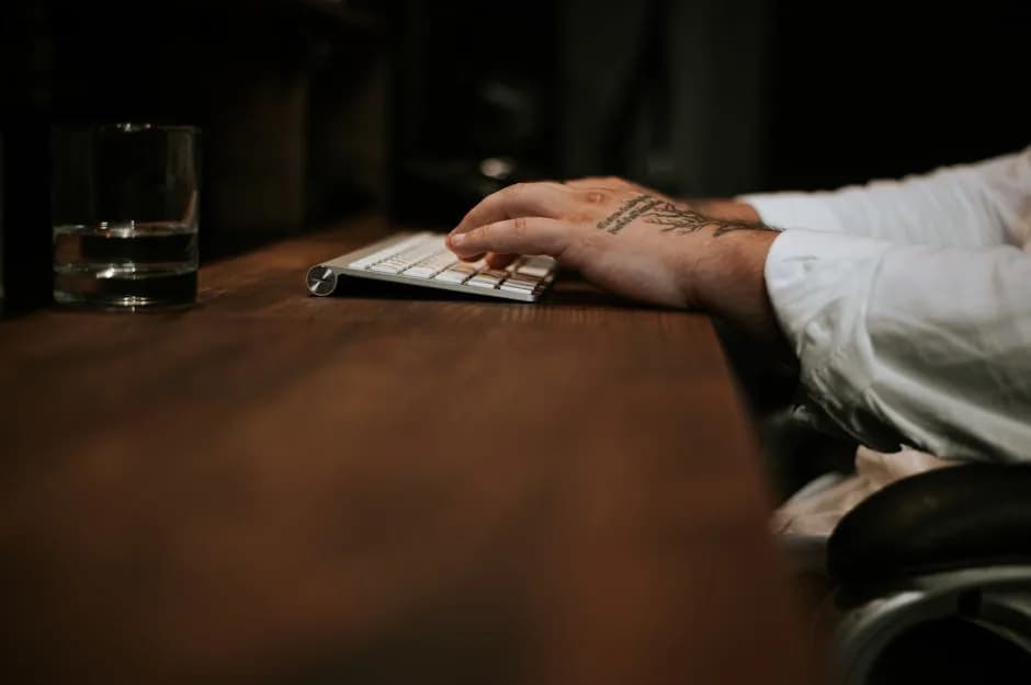 A UK jeweller weighing a fine gold bar at a workbench while preparing a VAT invoice