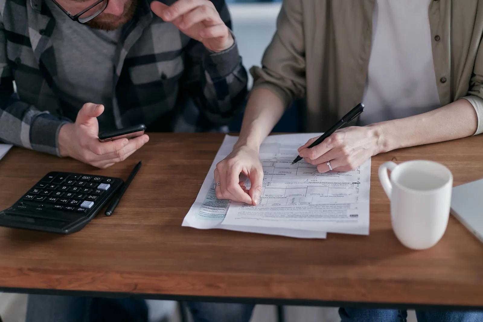 Couple reviewing tax forms together at a desk with a calculator and coffee