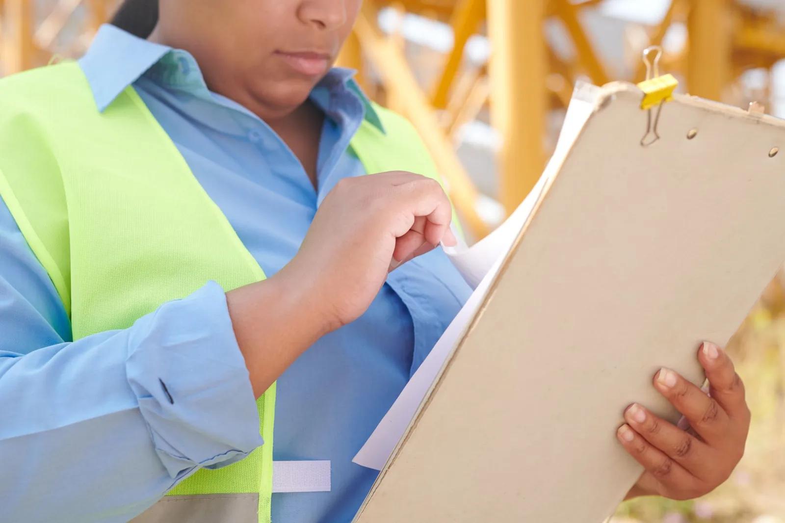 A construction contractor reviewing subcontractor payment records and an HMRC letter at a site office desk