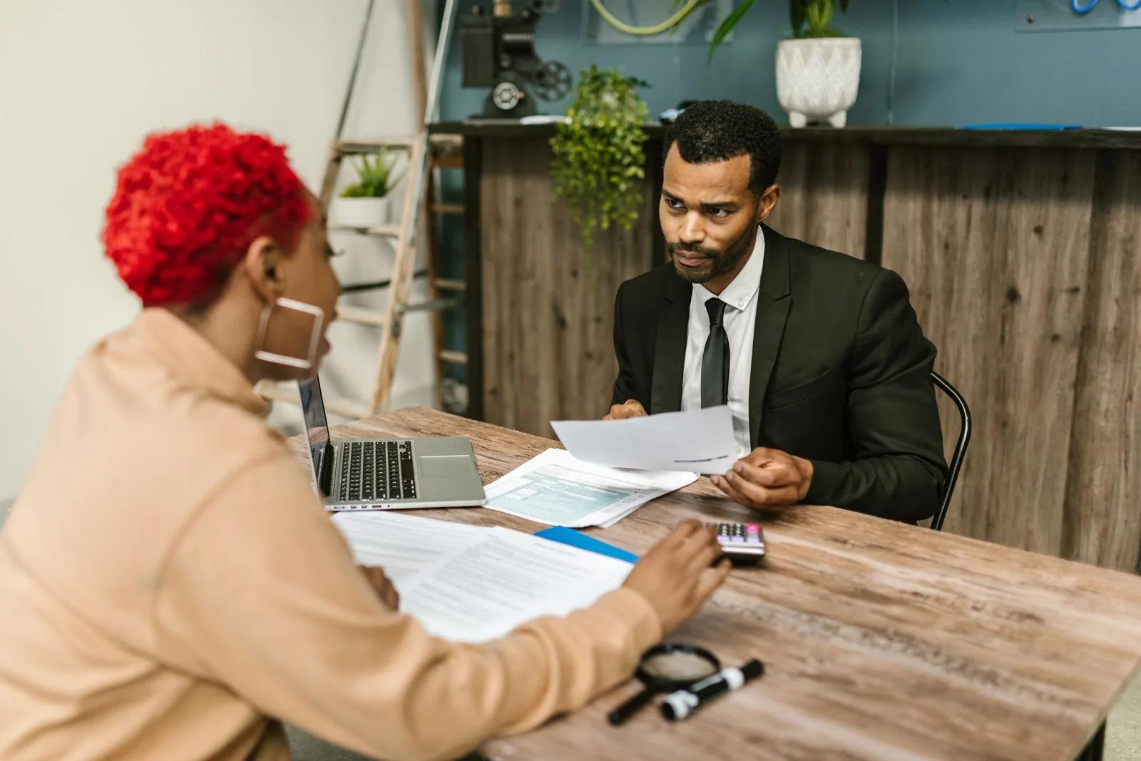 Two professionals reviewing financial documents together at a desk in a modern office