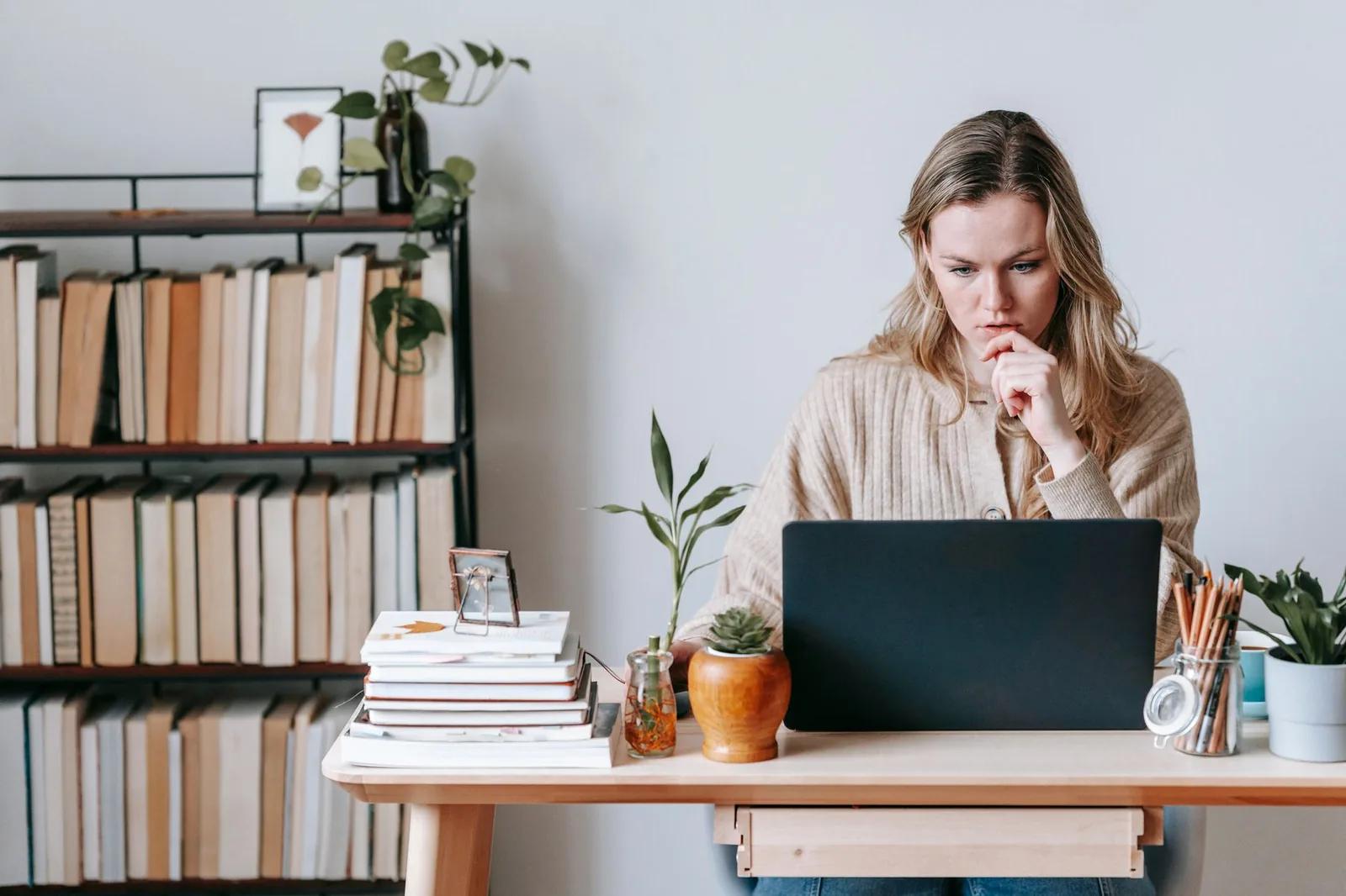 A self-employed sole trader reviewing their business figures on a laptop at a home office desk