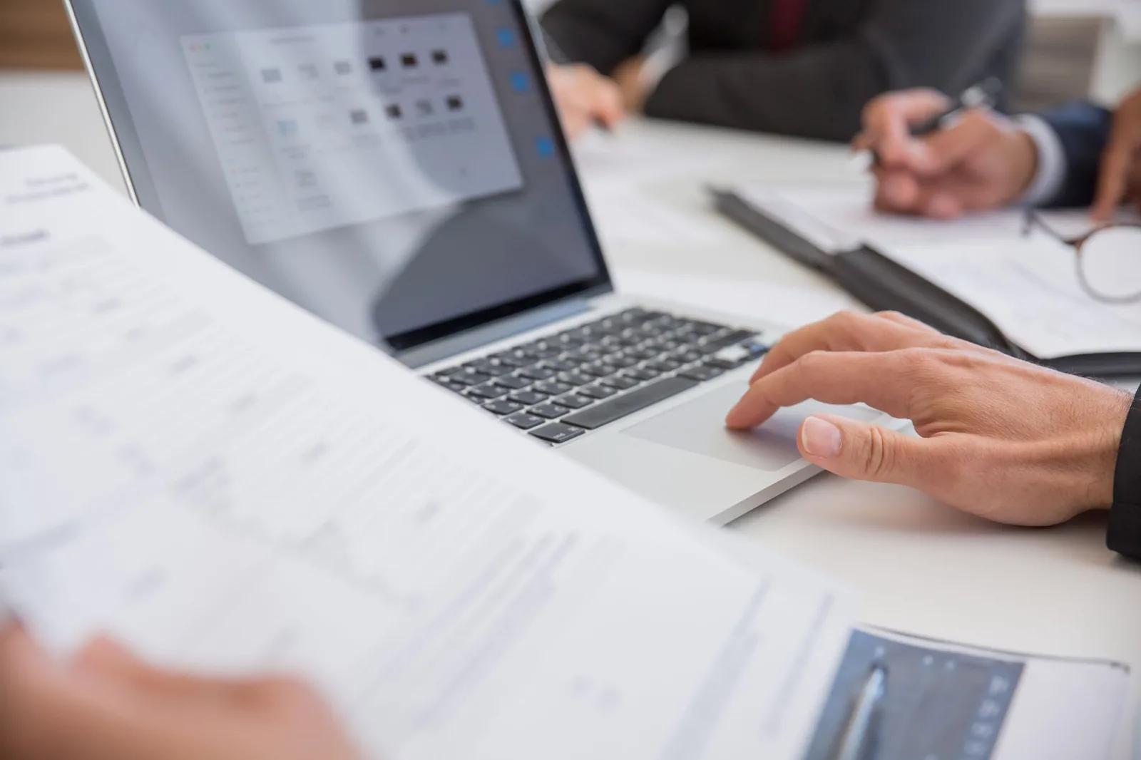 A UK accountant reviewing financial statements and internal control checklists side by side at a desk