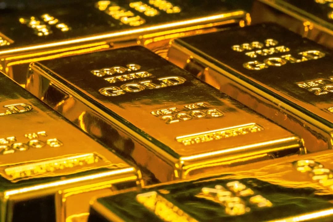 A jeweller weighing gold bullion bars and rings at a workbench to check VAT treatment