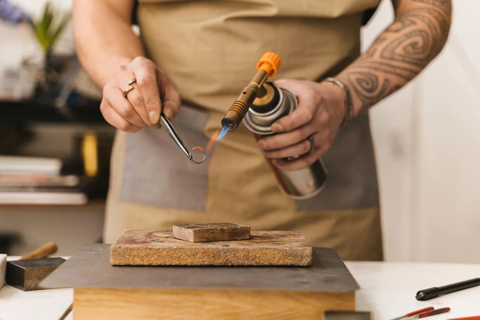 Jeweller using a torch to craft an unfinished ring at a workshop bench