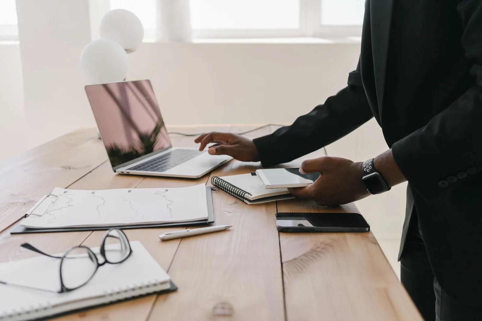 A UK landlord reviewing rental accounts and figures on a laptop with property paperwork and glasses on a desk