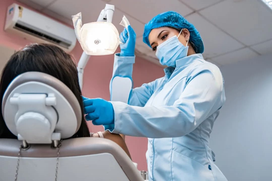 A dentist at a desk reviewing an NHS pension statement and tax paperwork on a laptop