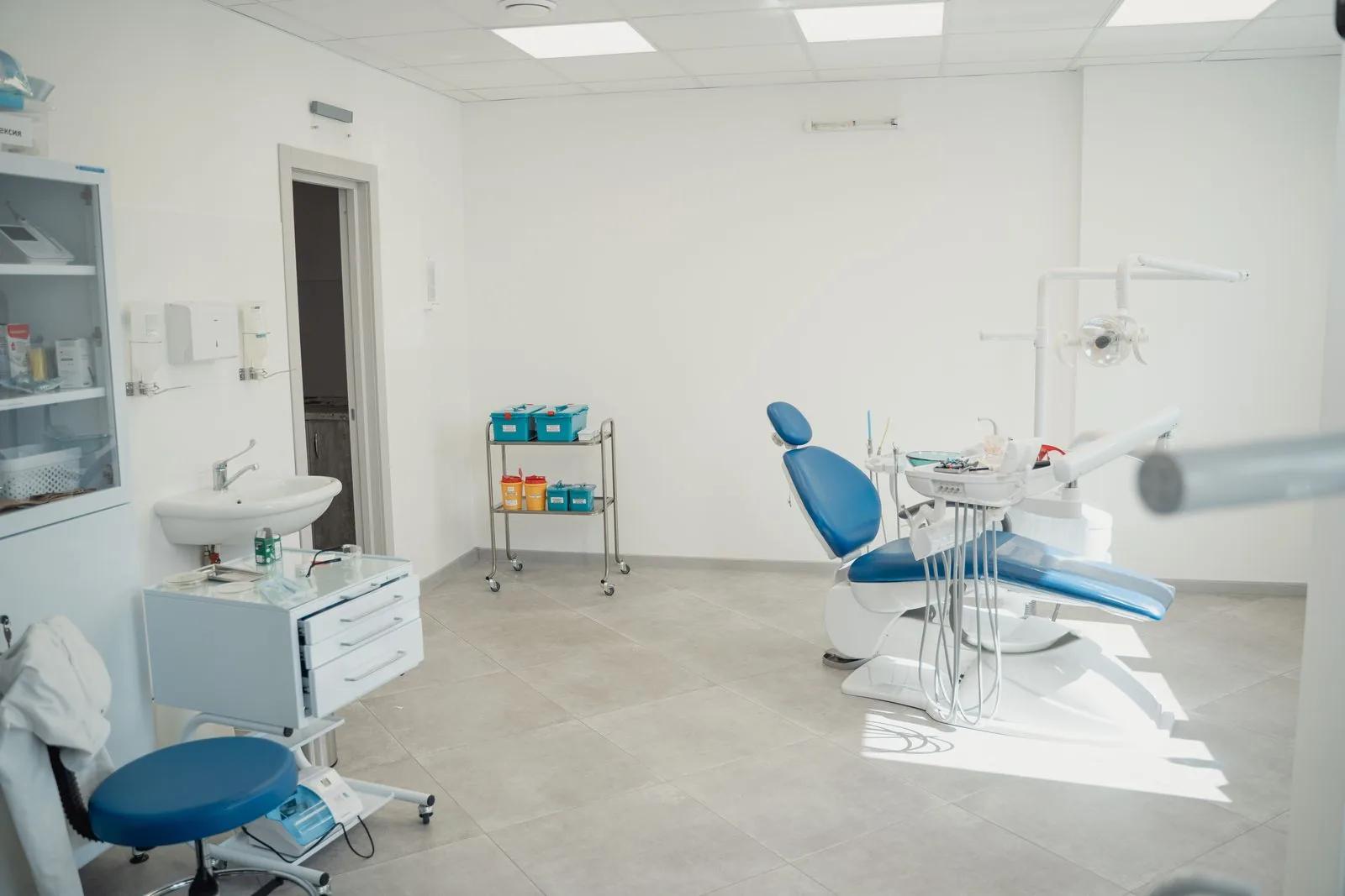 Bright modern dental surgery treatment room with dental chair and clinical equipment