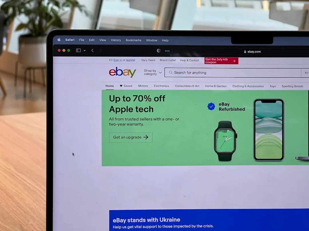 An eBay seller at a packing bench checking sales figures on a laptop to plan for Making Tax Digital