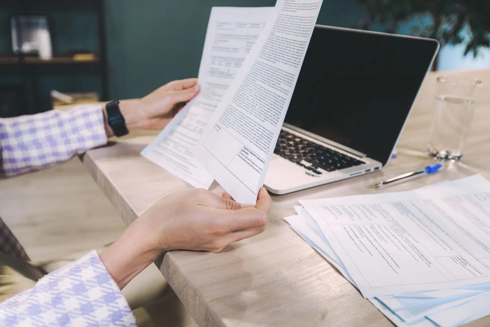 A UK sole trader at a laptop reviewing a 2026/27 tax calendar showing quarterly reporting deadlines alongside 31 January and 31 July payment dates