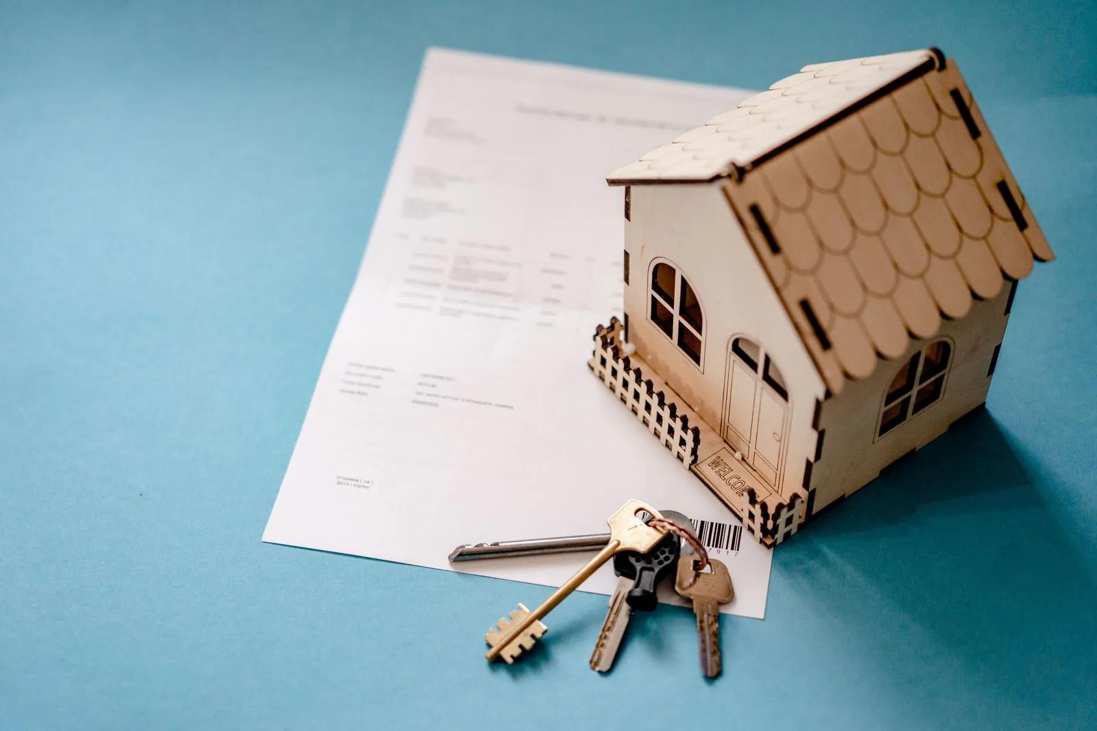 Model house with keys resting on a property document, signifying rental property paperwork