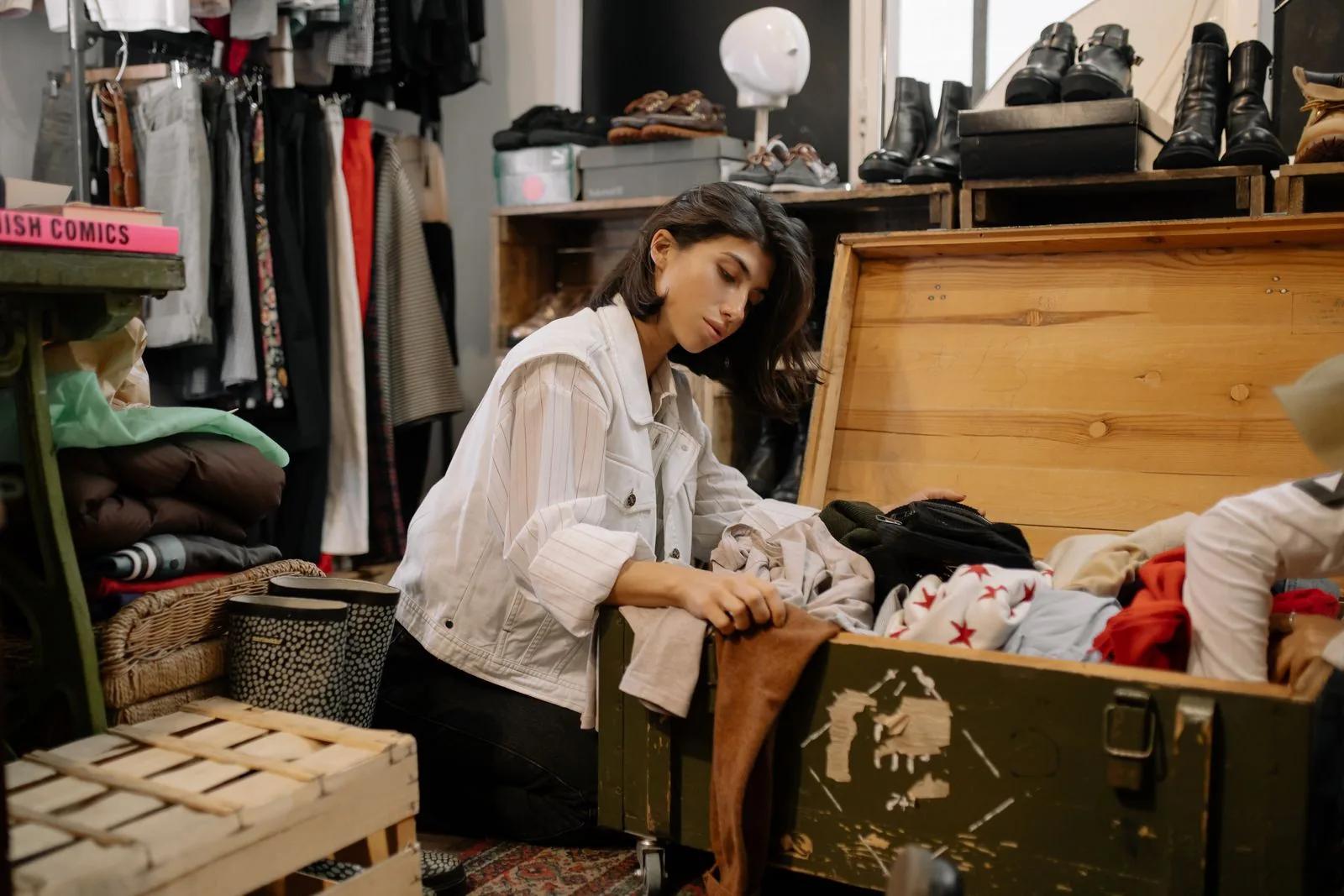 Reseller sorting secondhand garments and personal goods in a vintage thrift shop