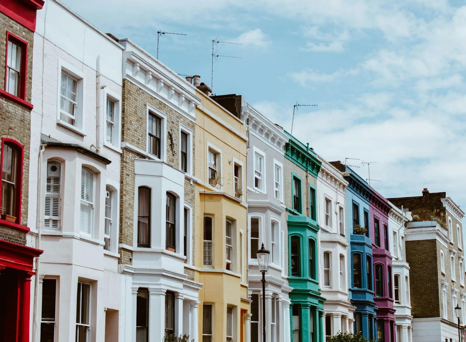 A row of brightly painted terraced houses on a London street under a blue sky