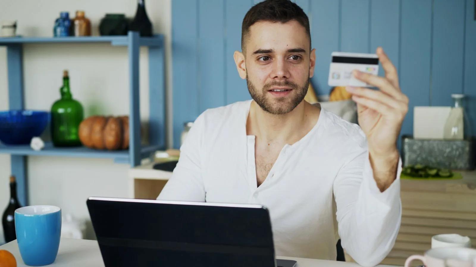 Man at a desk using a laptop and credit card to process an online payment
