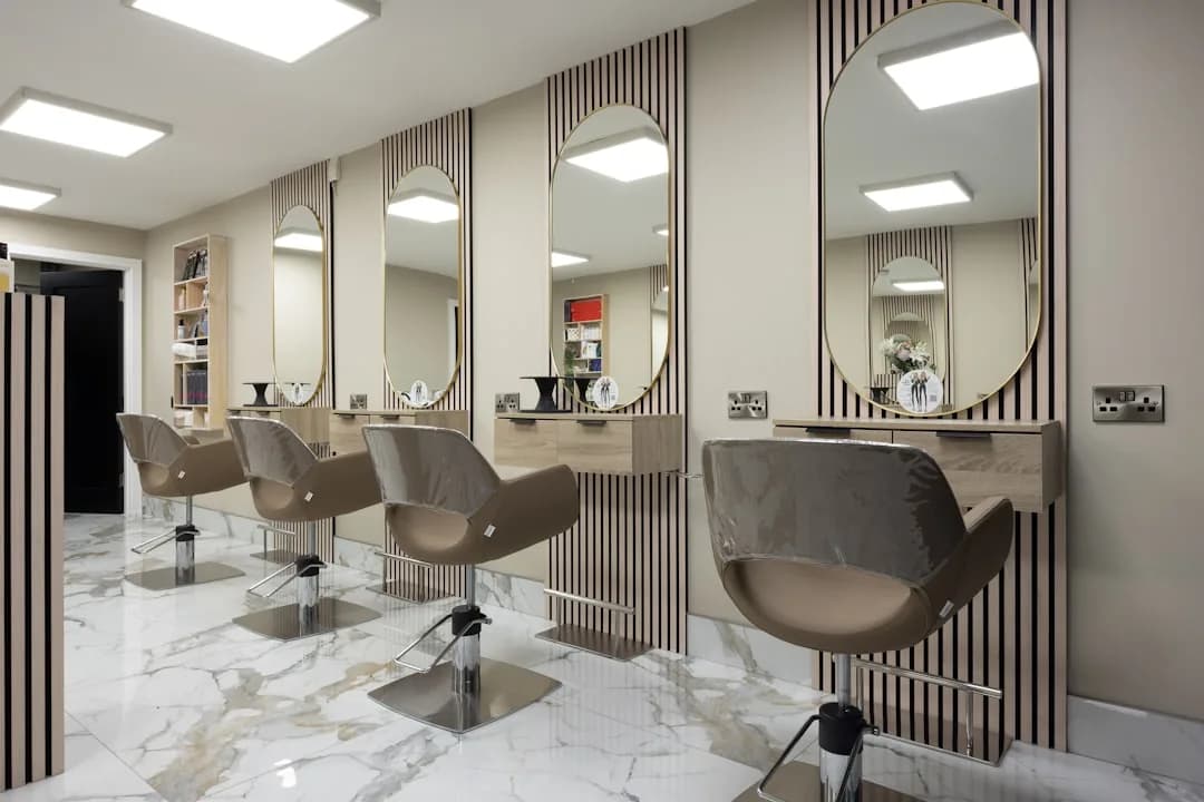 A hairdresser working at a rented chair in a busy salon, styling a client's hair