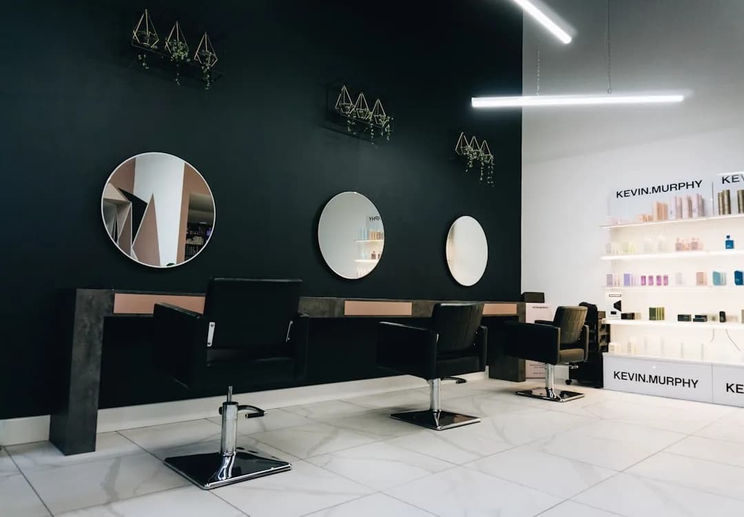A salon client tipping a hairdresser by card at the reception desk after an appointment