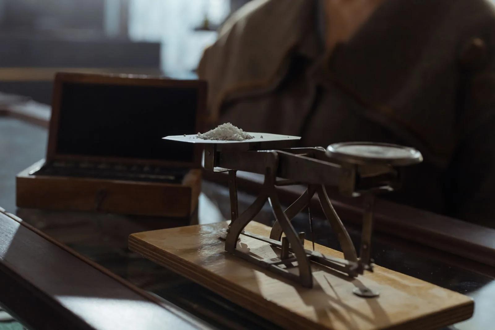 A classic balance weighing scale on a wooden surface, evoking precise weighing of precious metals