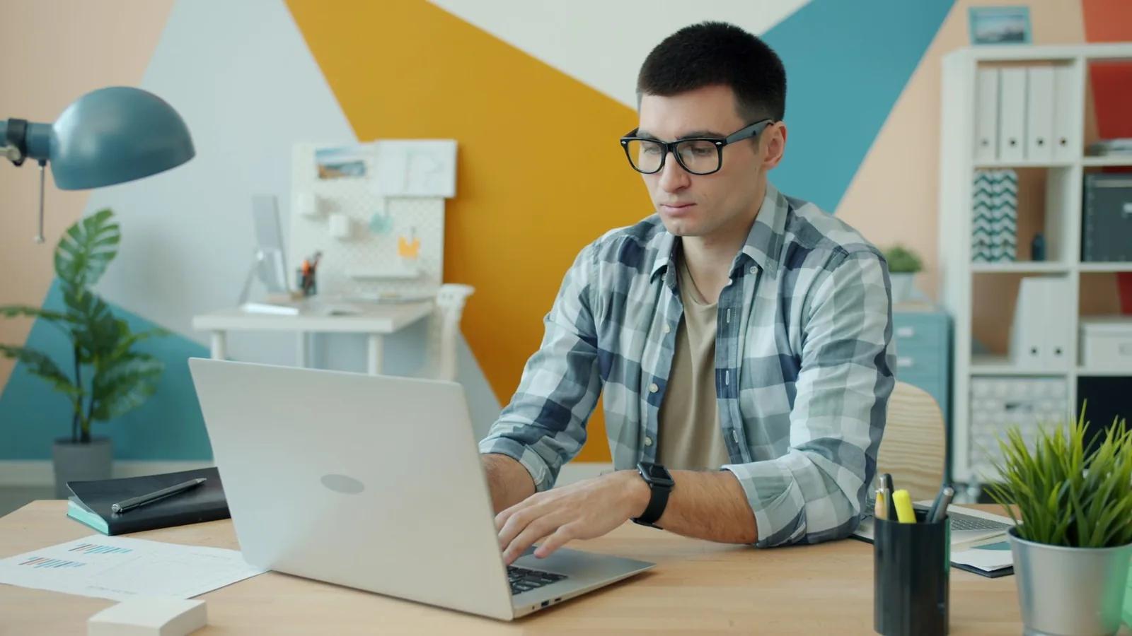 A self-employed freelancer updating their bookkeeping on a laptop at a tidy home-office desk