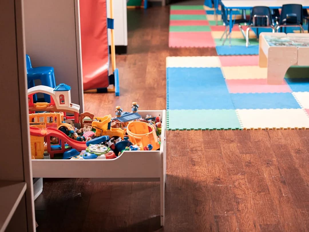 A childminder at a kitchen table reviewing childcare payment records and a tablet
