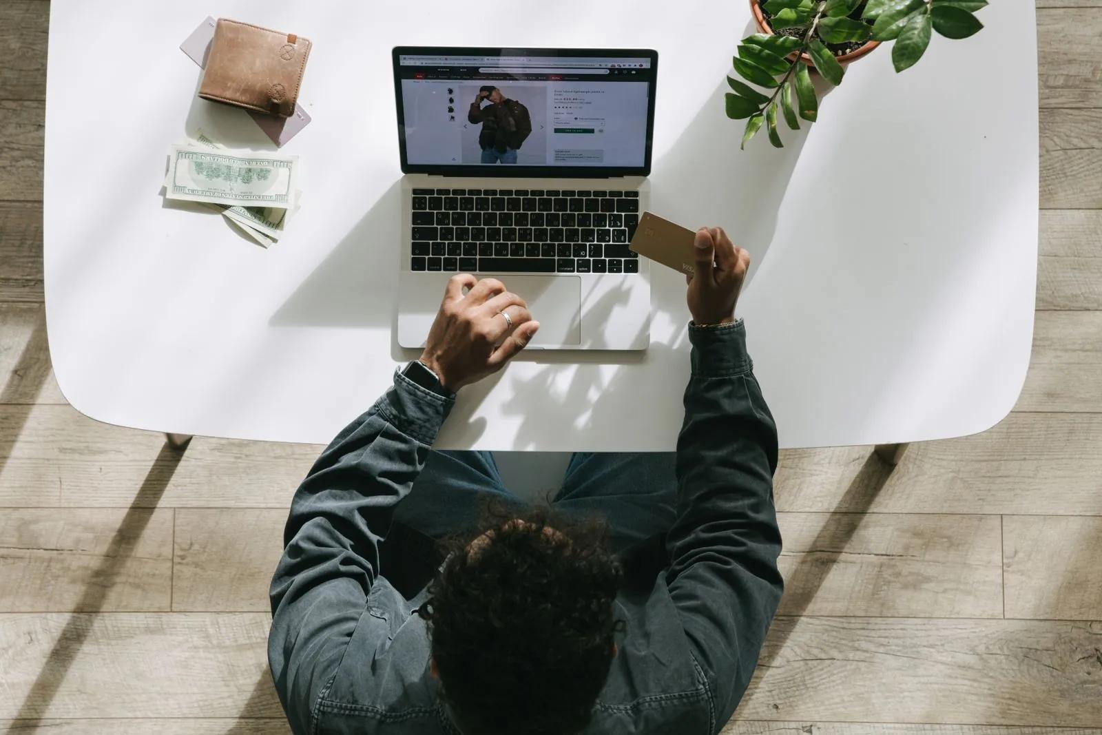 Person using a laptop and credit card to make an online payment at a bright desk