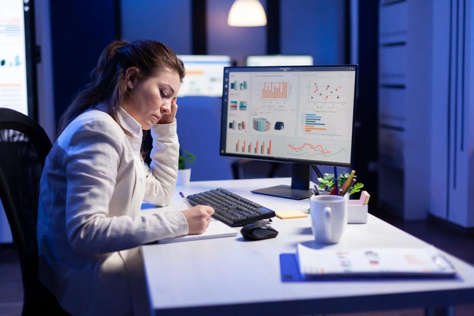 An accountant working at a desk with multiple monitors and documents.