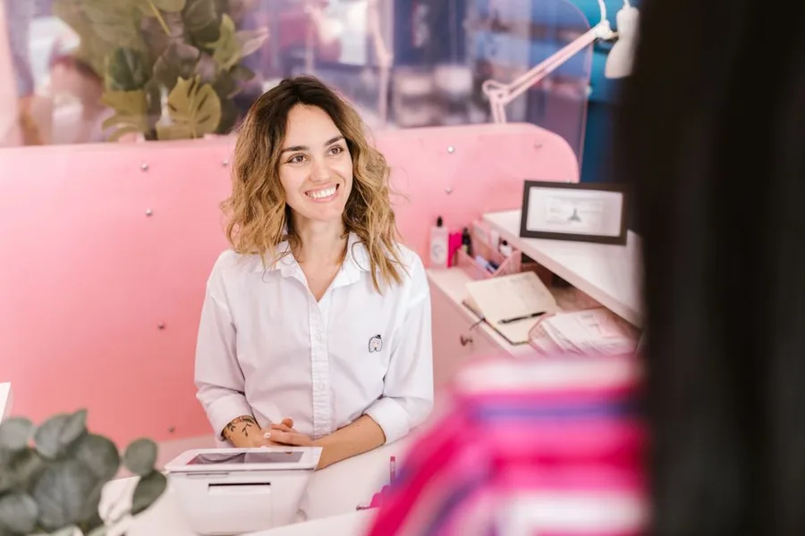 A salon owner at her reception desk with a tablet and appointment paperwork, handling the day's takings and admin A salon owner at her reception desk with a tablet and appointment paperwork, handling the day's takings and admin
