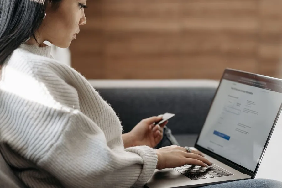 A small business owner making an online card payment on a laptop to settle affiliate commission owed to creators A small business owner making an online card payment on a laptop to settle affiliate commission owed to creators