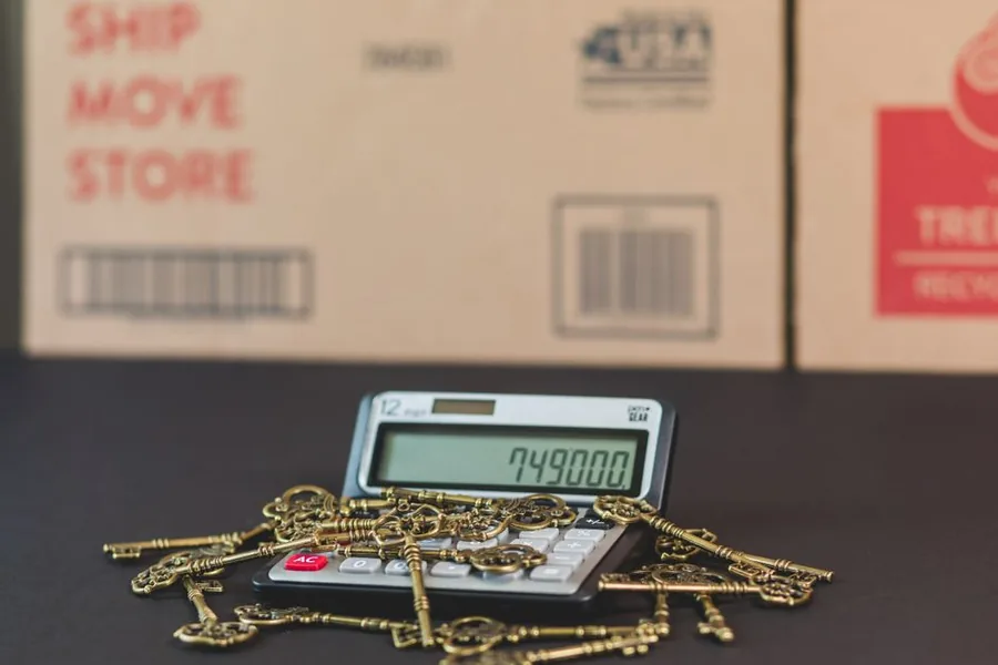 A desktop calculator beside shipping cartons, tallying freight, duty and import VAT into an ecommerce seller's landed cost A desktop calculator beside shipping cartons, tallying freight, duty and import VAT into an ecommerce seller's landed cost