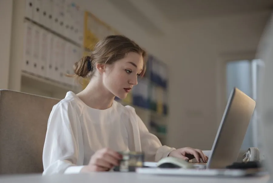 An ecommerce bookkeeper reconciling Amazon FBA returns and refunds on a laptop beside a shelf of accounts files An ecommerce bookkeeper reconciling Amazon FBA returns and refunds on a laptop beside a shelf of accounts files