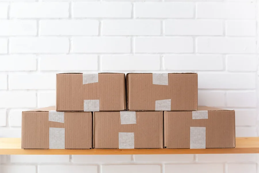 Neatly stacked plain cardboard parcels on a shelf, the kind of units an FBA seller ships during the Amazon peak fulfilment window