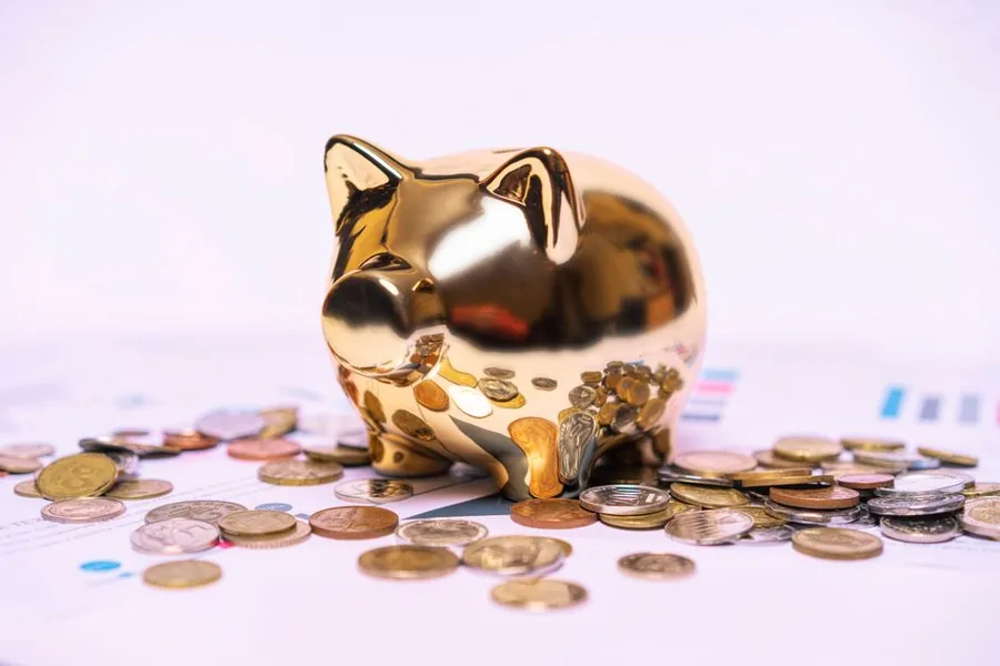 A golden piggy bank sitting on scattered coins and financial statements, symbolising long-term Lifetime ISA saving A golden piggy bank sitting on scattered coins and financial statements, symbolising long-term Lifetime ISA saving