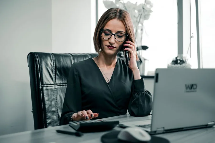 A small business owner checking her turnover on a calculator while phoning her accountant about VAT deregistration A small business owner checking her turnover on a calculator while phoning her accountant about VAT deregistration